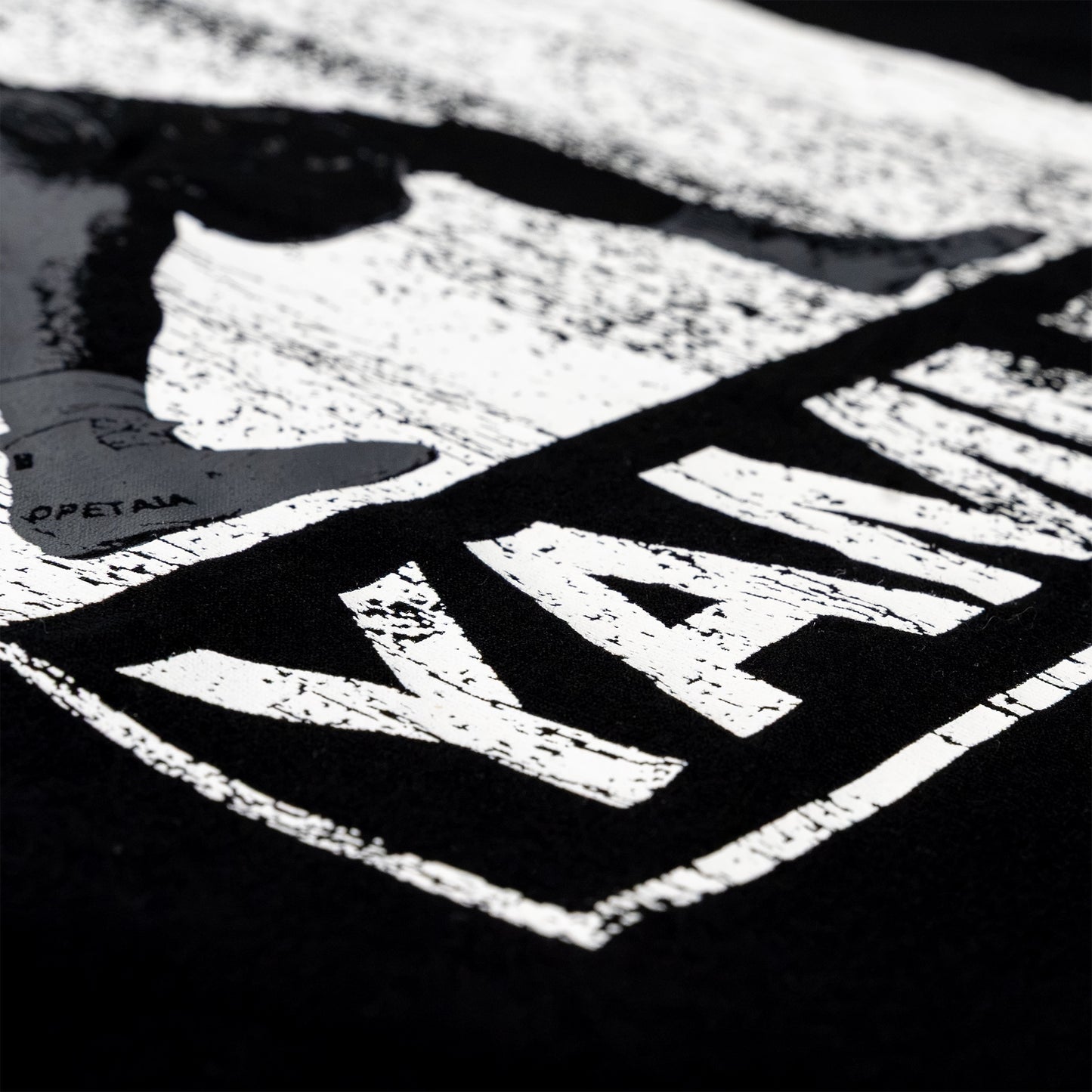 Close-up of a black garment featuring a large distressed white graphic print with the wordmark 'YAMMY' and a shoe silhouette.