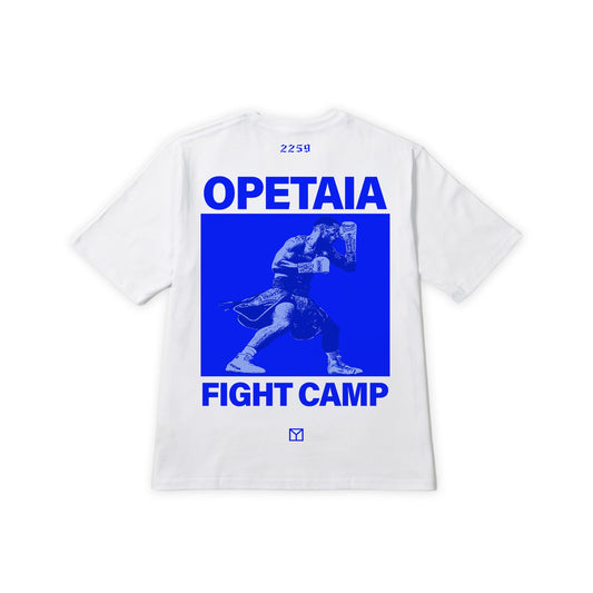 A white short-sleeve t-shirt shown flat against a white background, featuring a large blue graphic print on the back with the text 'OPETAIA FIGHT CAMP' and a blue-toned illustration of a martial artist.