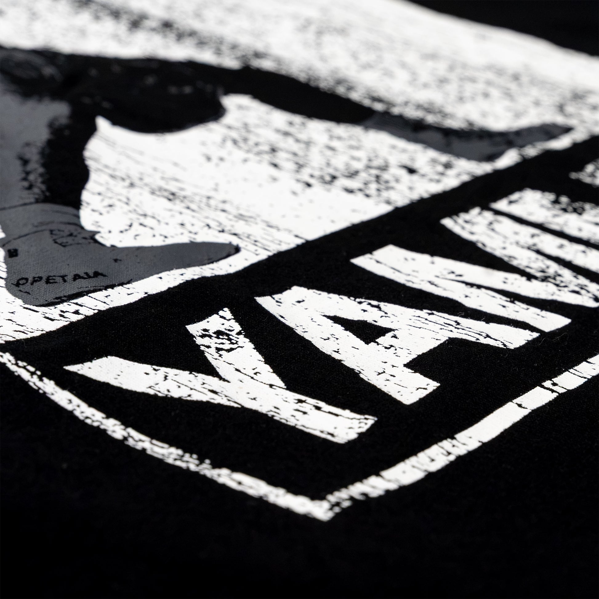 Close-up of a black garment featuring a large distressed white graphic print with the wordmark 'YAMMY' and a shoe silhouette.
