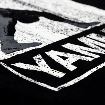 Close-up of a black garment featuring a large distressed white graphic print with the wordmark 'YAMMY' and a shoe silhouette.