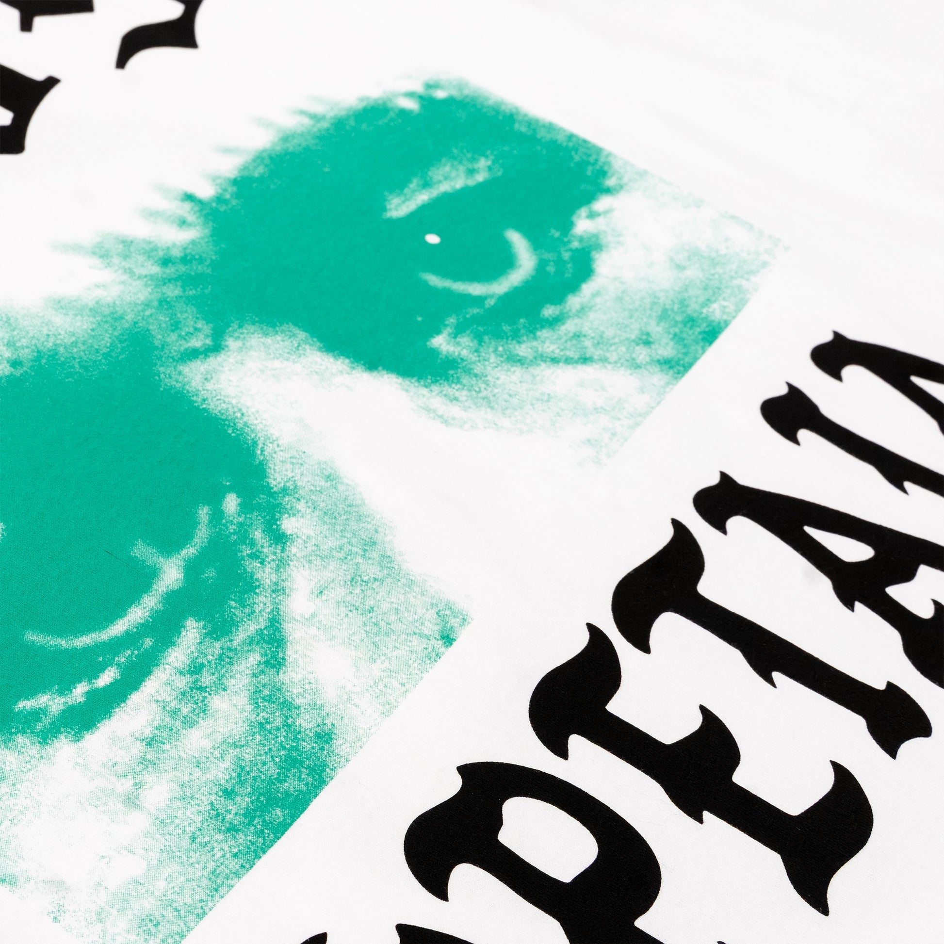 Close-up of a white graphic print featuring a textured mint green abstract design and bold black gothic lettering.