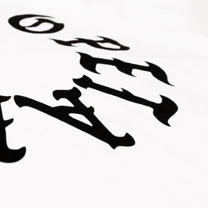 A close-up of a white fabric surface featuring a black gothic-style letter print, showing part of the word 'OPETAIA' in a bold, stylized font.