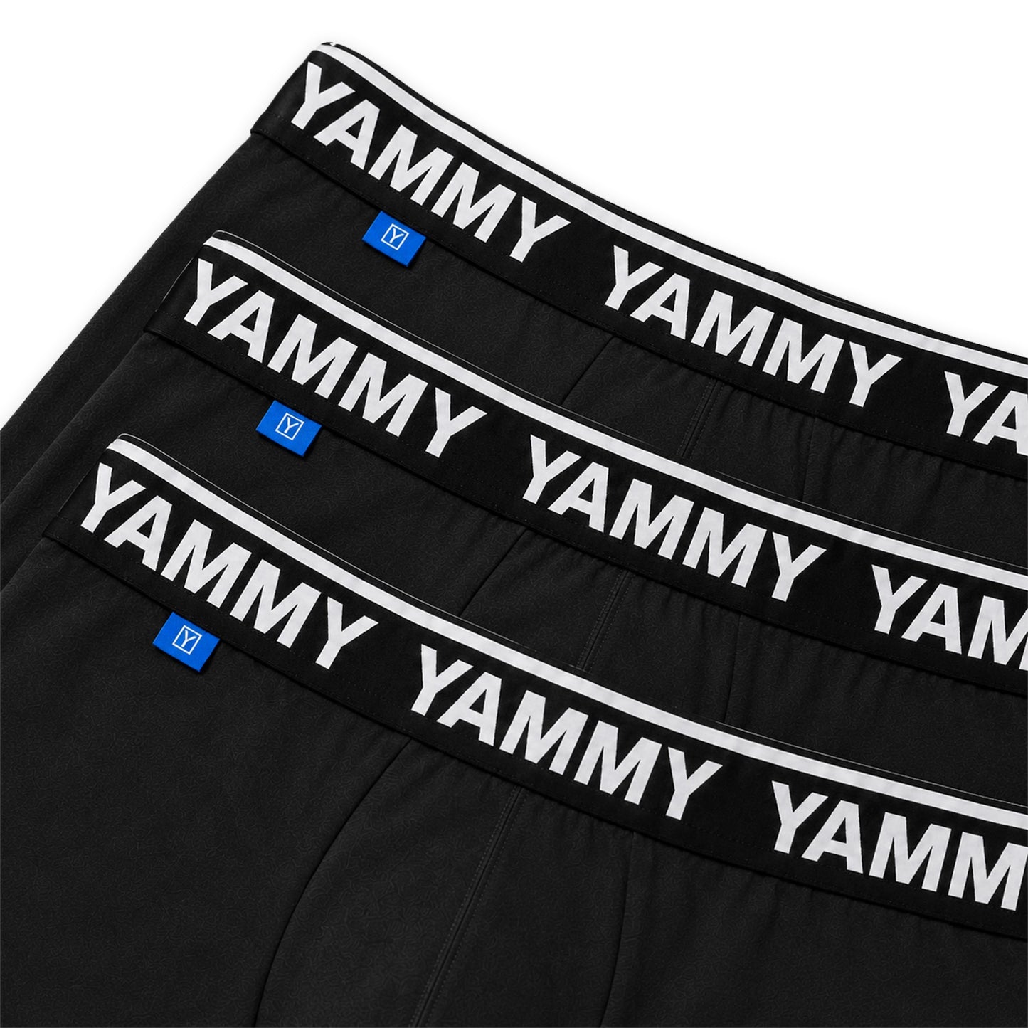 Three pairs of black boxer briefs stacked diagonally, featuring a wide black waistband with 'YAMMY' printed repeatedly in white and a small blue brand tag.