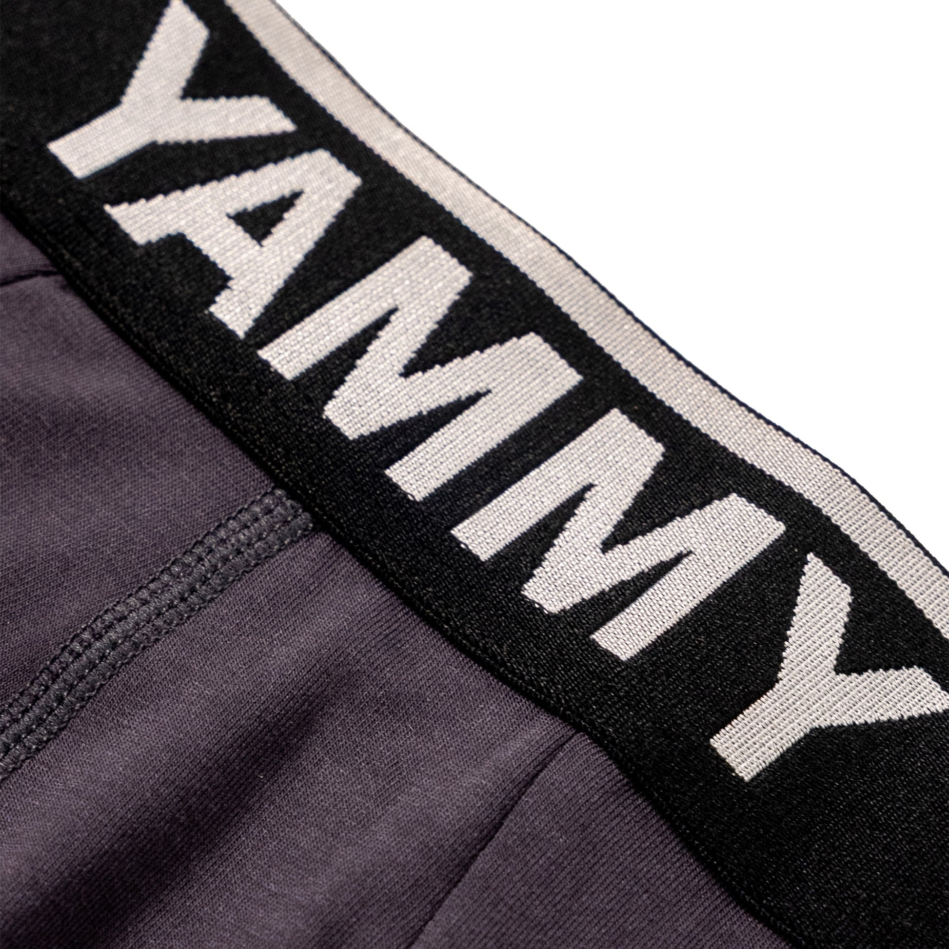 Close-up of a dark gray athletic garment with a wide black waistband featuring the word 'YAMMY' in large white letters.