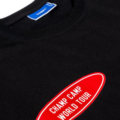 Close-up of a black T-shirt showing the inner neck label with 'YAMMY' and a red oval chest graphic with white text reading 'CHAMP CAMP WORLD TOUR'.