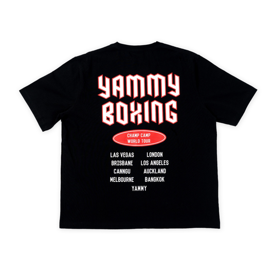 A black short-sleeve t-shirt shown from the back, featuring a large graphic print with the words 'YAMMY BOXING' in white outlined red letters, a red oval badge reading 'CHAMP CAMP WORLD TOUR', and a list of tour cities in white text below.
