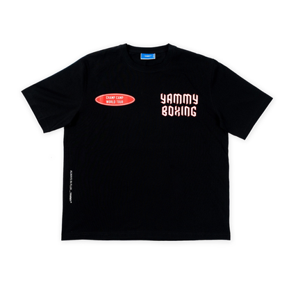 A black short-sleeve t-shirt with a red oval graphic on the left chest reading 'CHAMP CAMP WORLD TOUR' and 'YAMMY BOXING' in a red background and white font on the right chest, displayed flat against a white background.