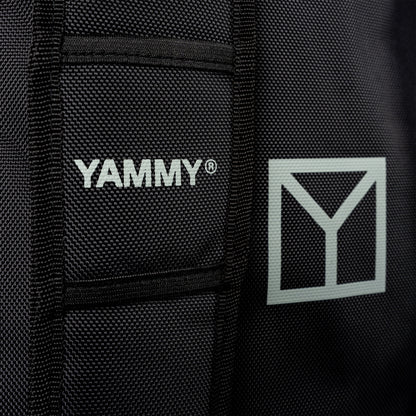 Close-up of a black textured fabric product with white YAMMY branding and a white geometric Y logo on the side.