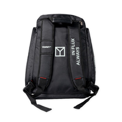 Black backpack shown from the back, featuring white printed branding including 'YAMMY', a large Y logo, and 'ALWAYS IN FLUX' on the shoulder straps, set against a plain white background.