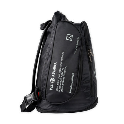 A black nylon backpack with white printed text and logos, including 'YAMMY' and 'COMBAT STUDIOS', shown on a plain white background.