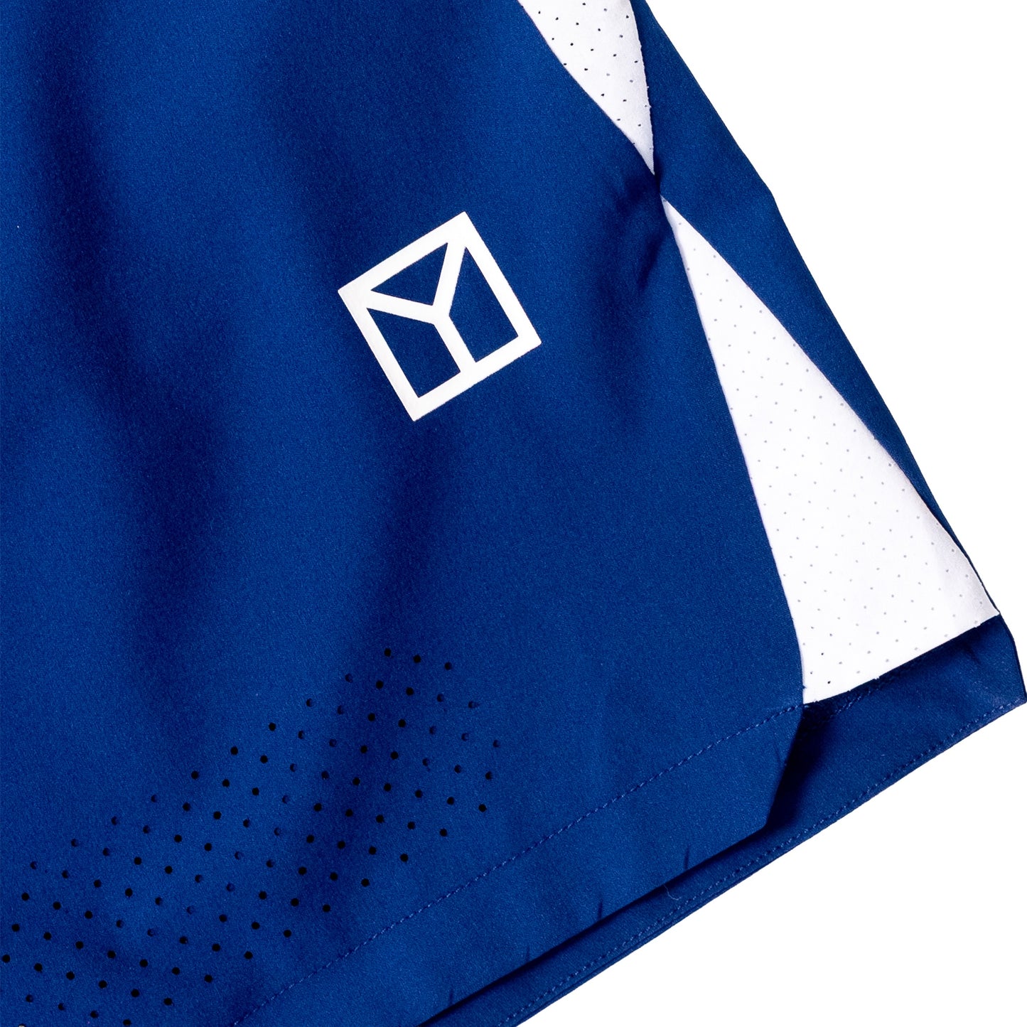 Close-up of a royal blue athletic garment, likely a shorts leg or towel, featuring a white geometric logo, white mesh side panels, and black perforation details on a white background.