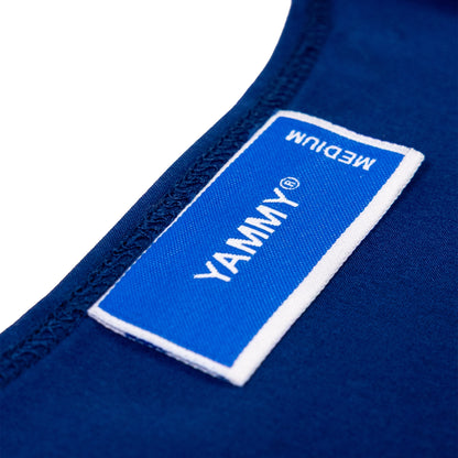 Close-up of a blue fabric garment label with white trim and white text reading 'YAMMY' and 'MEDIUM', attached to dark blue clothing on a white background.