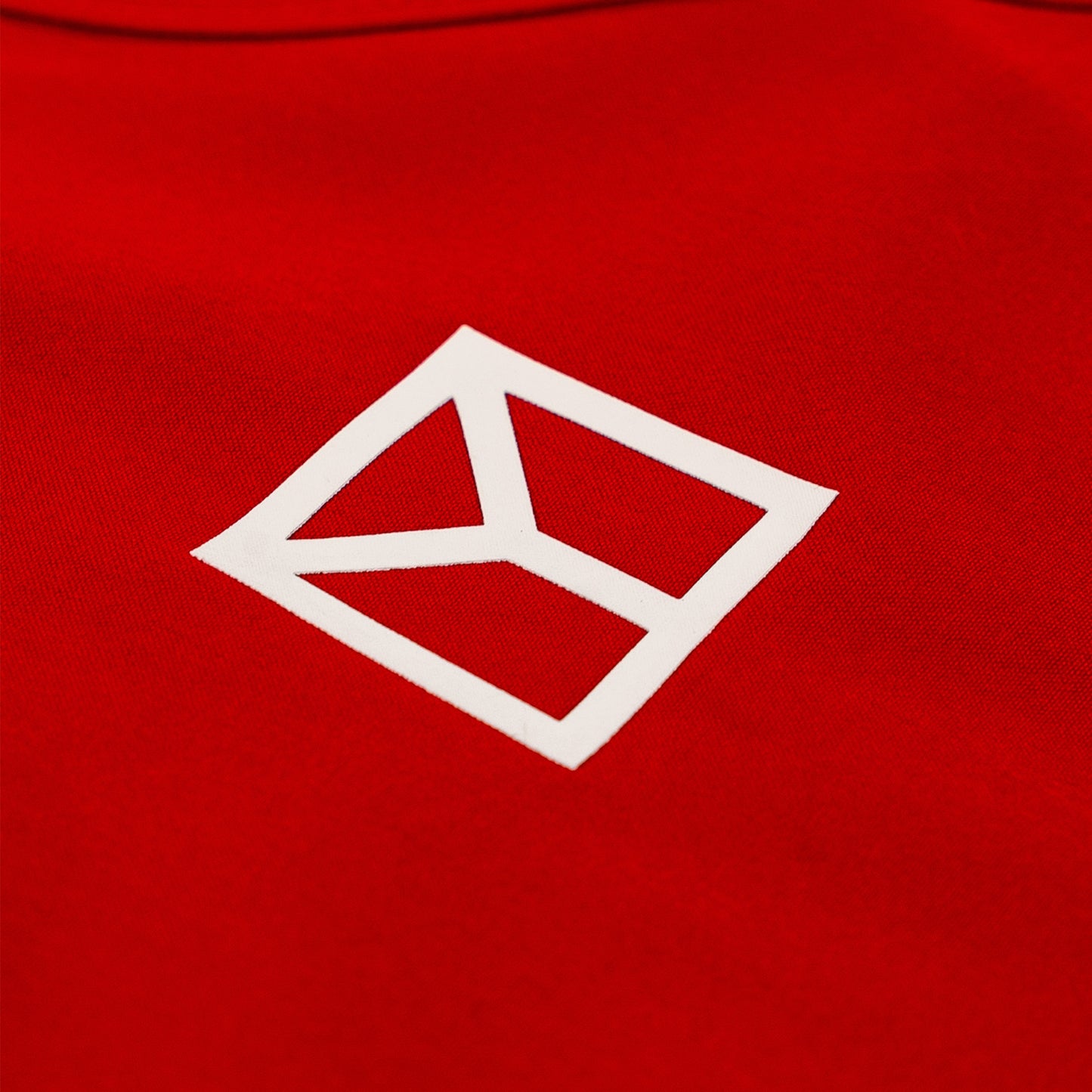 Close-up of a bright red fabric surface with a white geometric logo outlined in a diamond shape.
