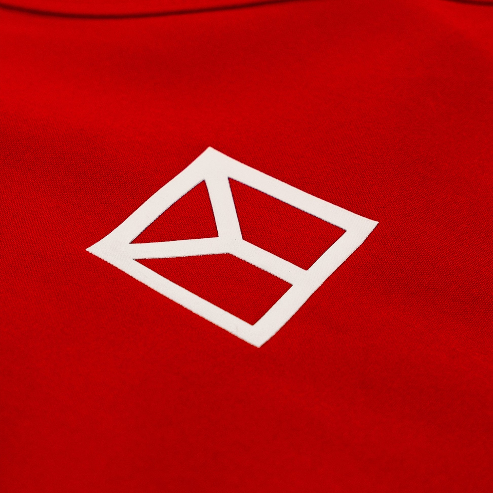 Close-up of a bright red fabric surface with a white geometric logo outlined in a diamond shape.