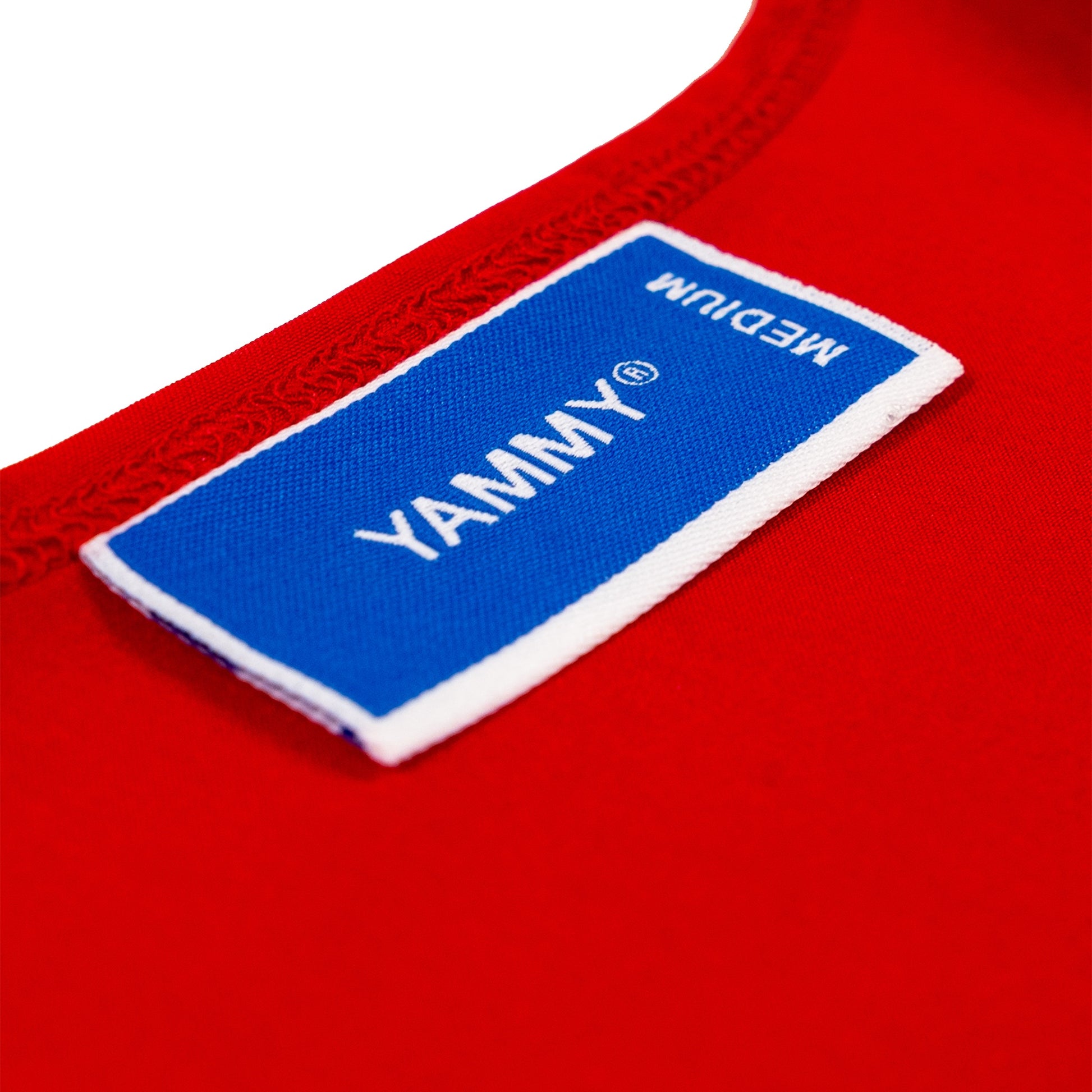 Close-up of a red garment with a blue and white fabric label reading YAMMY and MEDIUM.