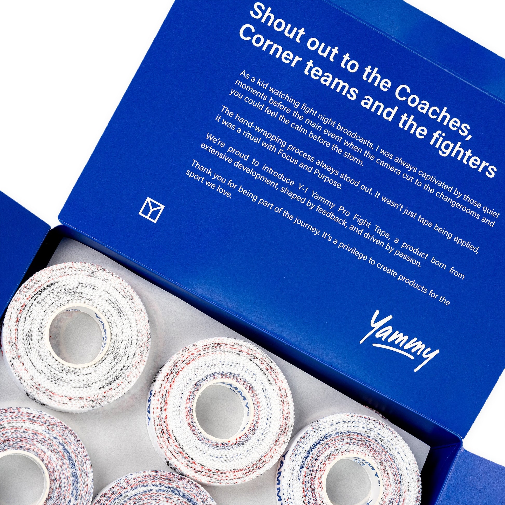 An open blue Yummy Fight Tape gift box showing several rolls of white fight tape with red and blue speckles inside, with the inner lid displaying a white printed message.
