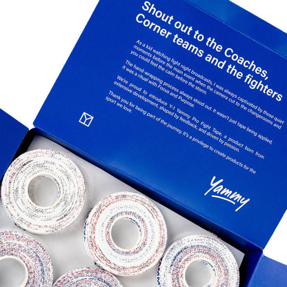 An open blue Yummy Fight Tape gift box showing several rolls of white fight tape with red and blue speckles inside, with the inner lid displaying a white printed message.